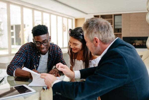 Investment Advisor Insurance - Young Couple Talking With a Financial Advisor Offering Advice and Financial Counseling While Using a Digital Tablet in the Office
